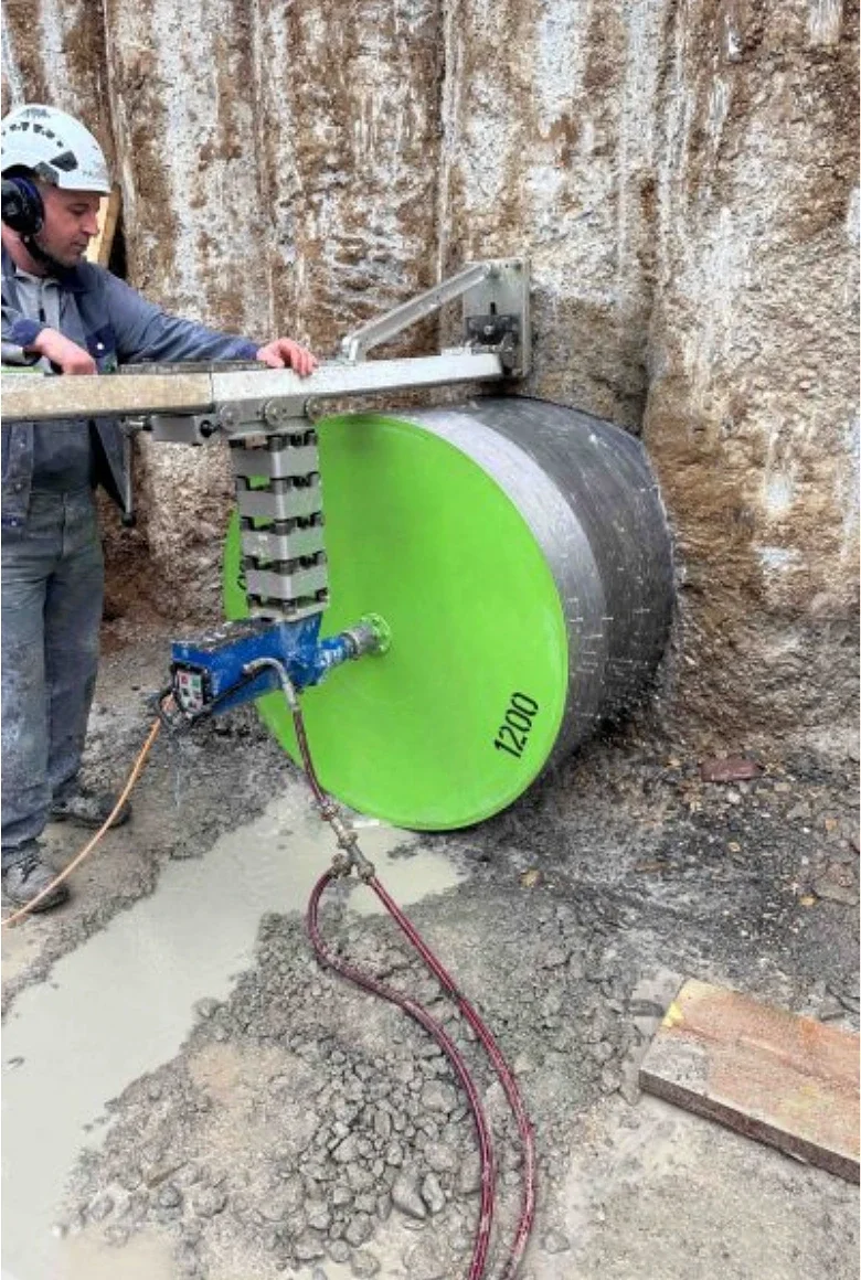 Byggarbetare använder stor grön diamantskiva för att skära betongvägg.